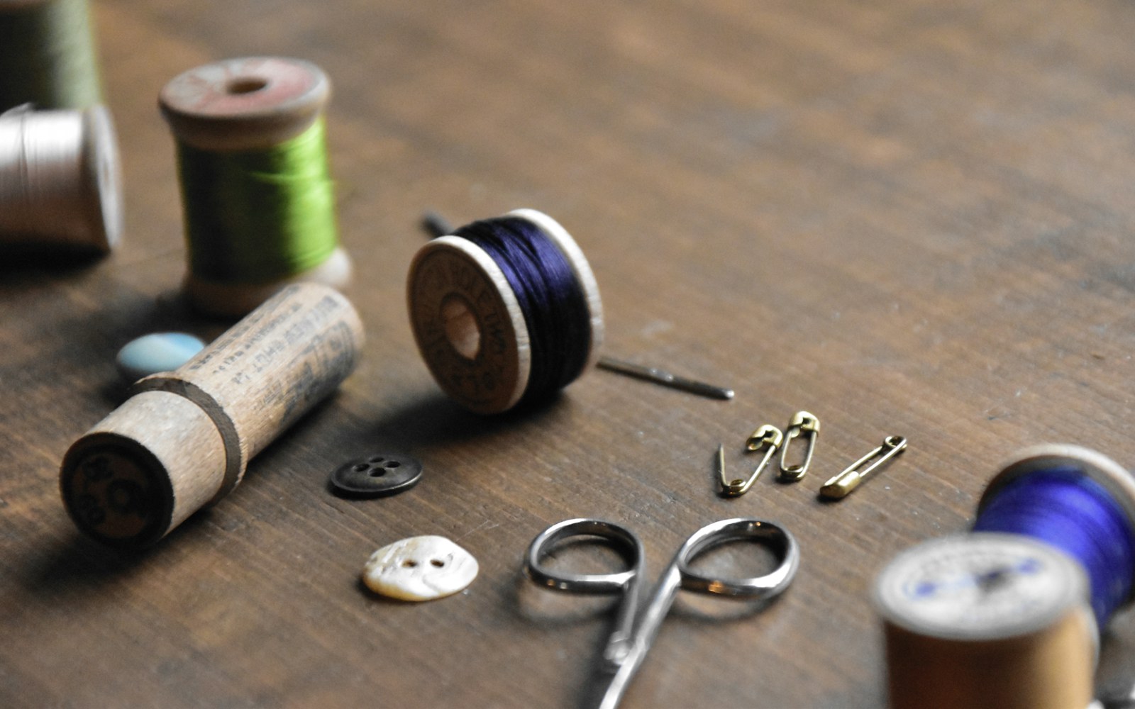 Close-up of hands measuring fine fabric and arranging miniature pattern pieces beside a small dressed art doll.