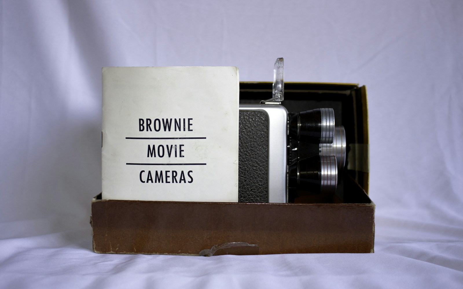 A handmade mixed-media art doll beside a notebook, archival document sleeve, ruler, and camera on a clean worktable.