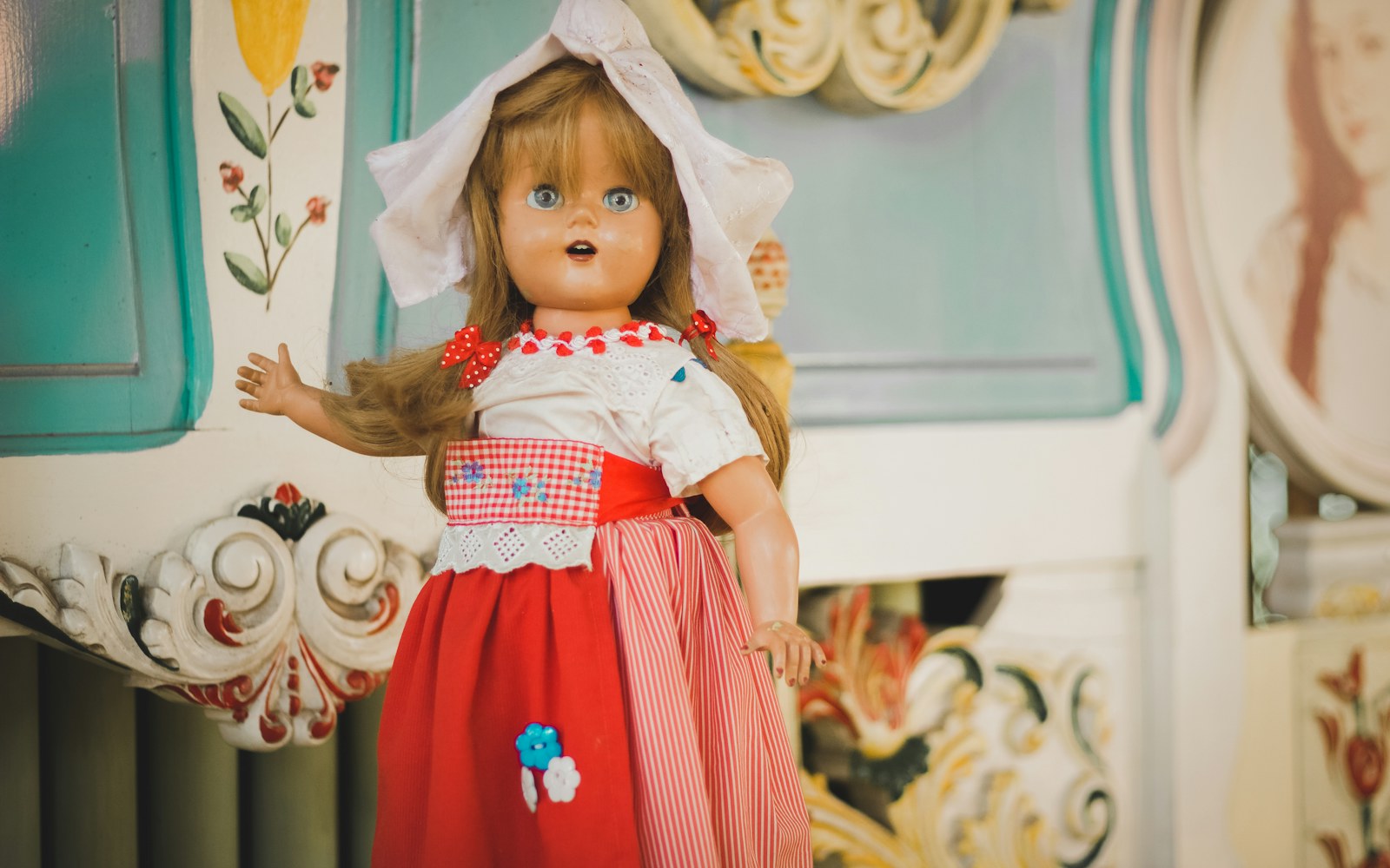 A handmade art doll beside a notebook, archival folders, a camera, and labeled documentation cards on a worktable.
