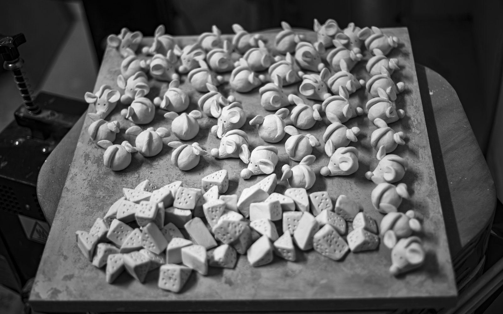 Small handmade figures in felted wool, polymer clay and sewn fabric arranged on a worktable with simple tools