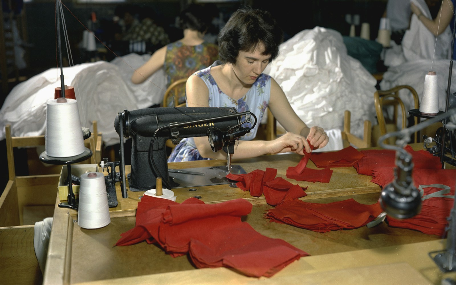 Close view of a long cream fleece soft sculpture form laid on a worktable with sewing tools and paint swatches.