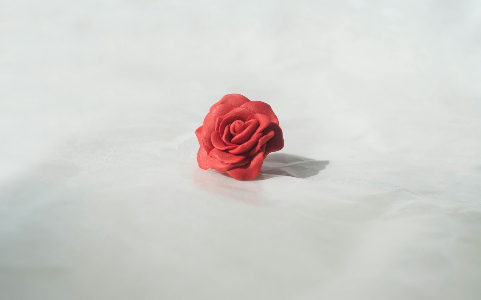 Close-up of a small polymer clay figure and labeled test tiles showing iridescent color-shifting surface finishes under angled light.