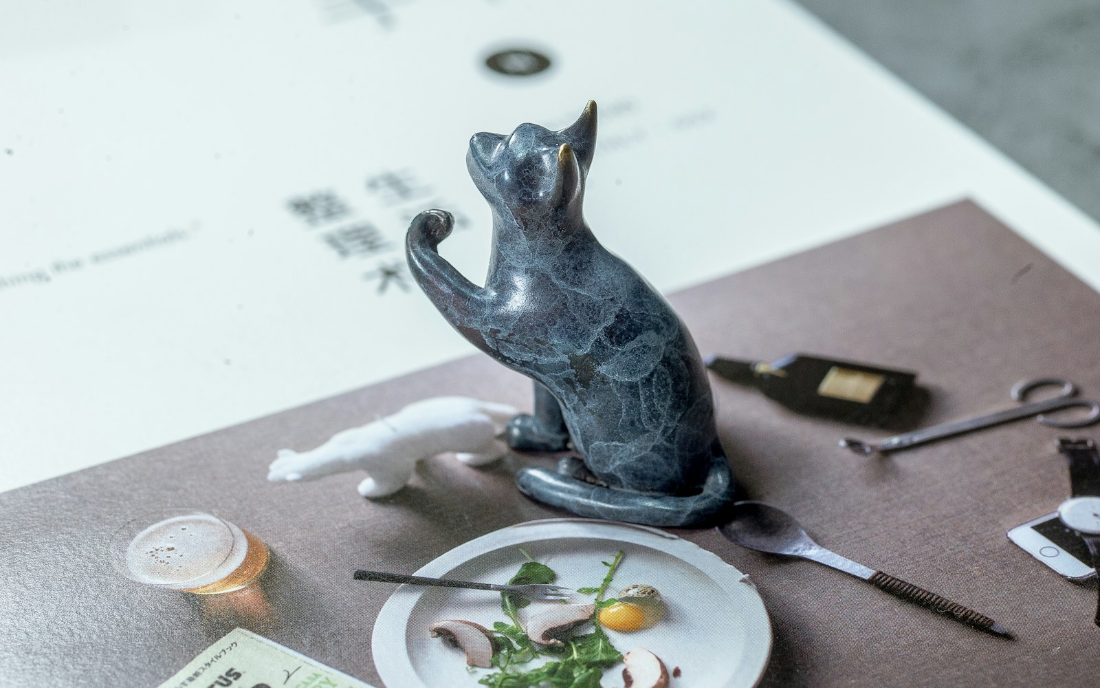 A handmade pet figure beside reference photographs, a collar, and small craft tools on a worktable