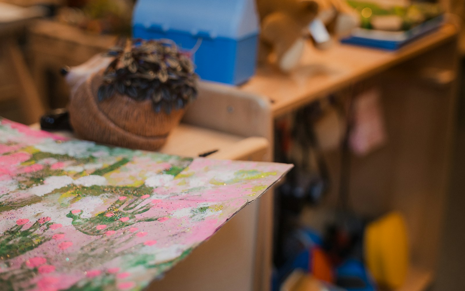 A collector’s hands organizing photographs, labels, and material notes beside a handmade art doll on a clean worktable.