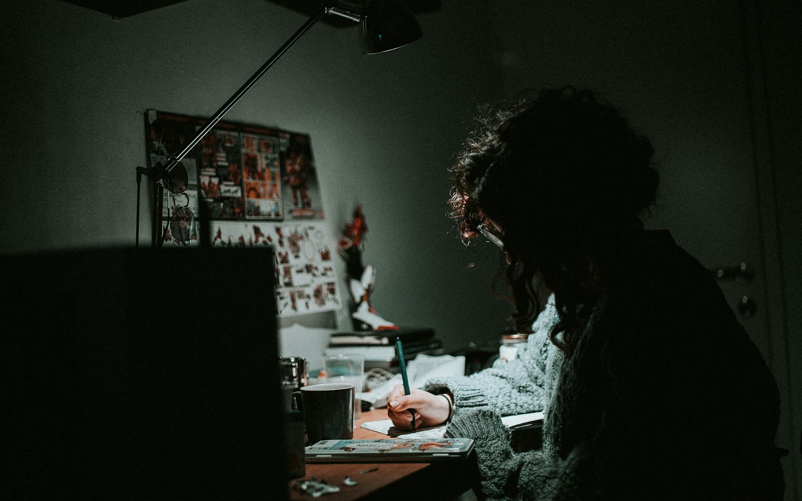 A handmade art doll beside a notebook, labeled archival folders, a camera, and carefully arranged accessories on a worktable.