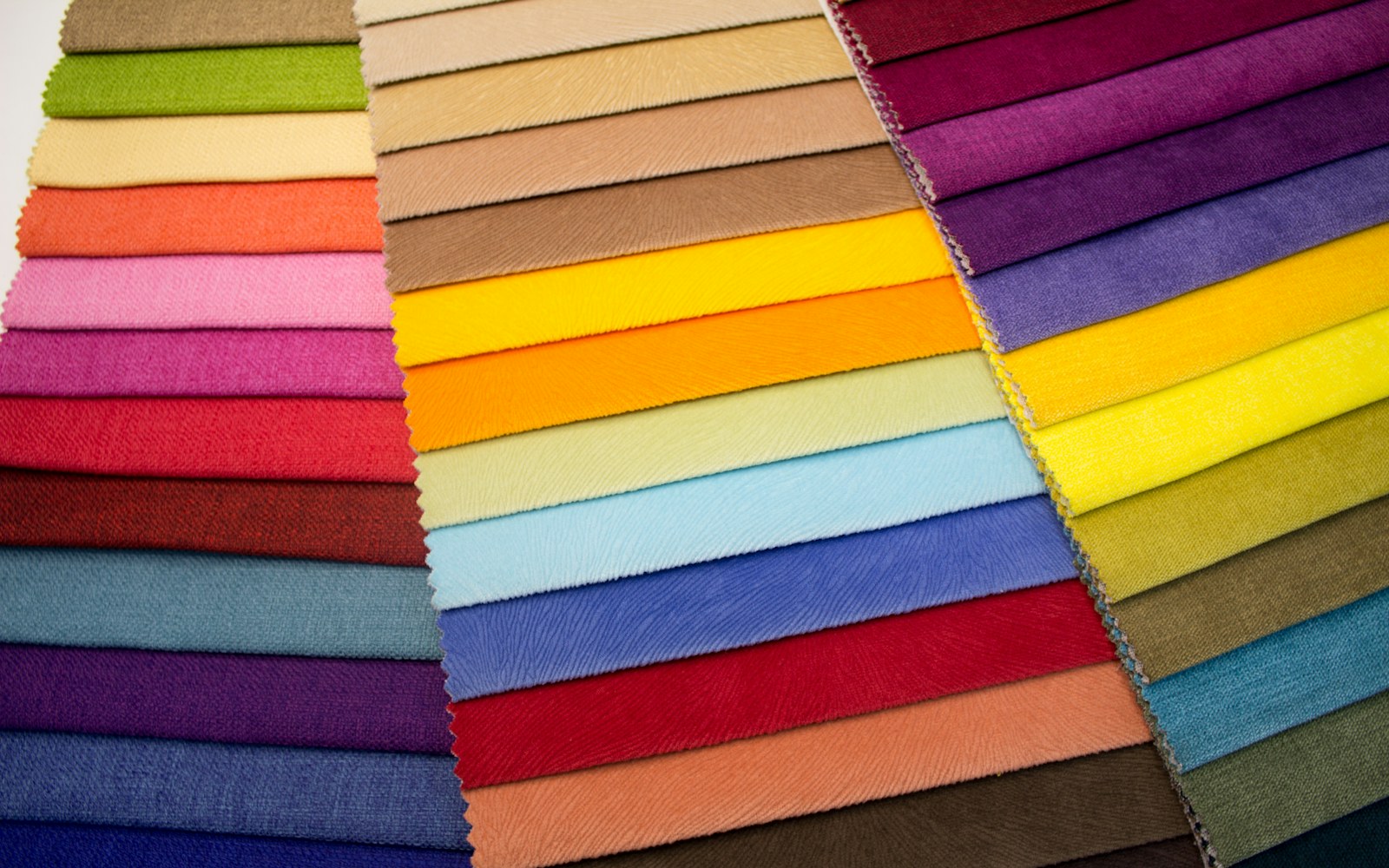 Close-up of fabric swatches and small pattern pieces for doll clothing on a neutral work surface