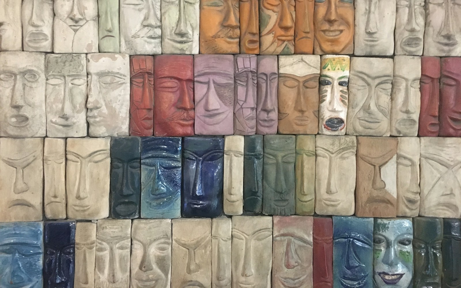 Ceramic doll head and test tiles with milky translucent glaze on a studio table
