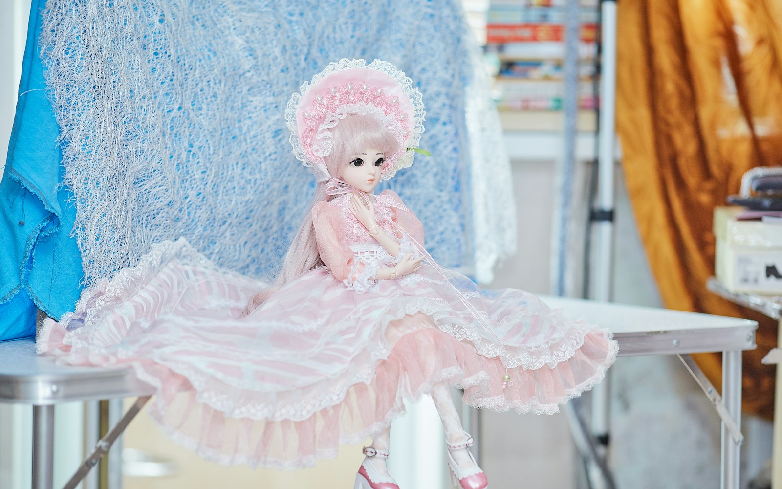 Hands shaping a stuffed textile doll body beside fabric pieces, batting and a simple wire armature