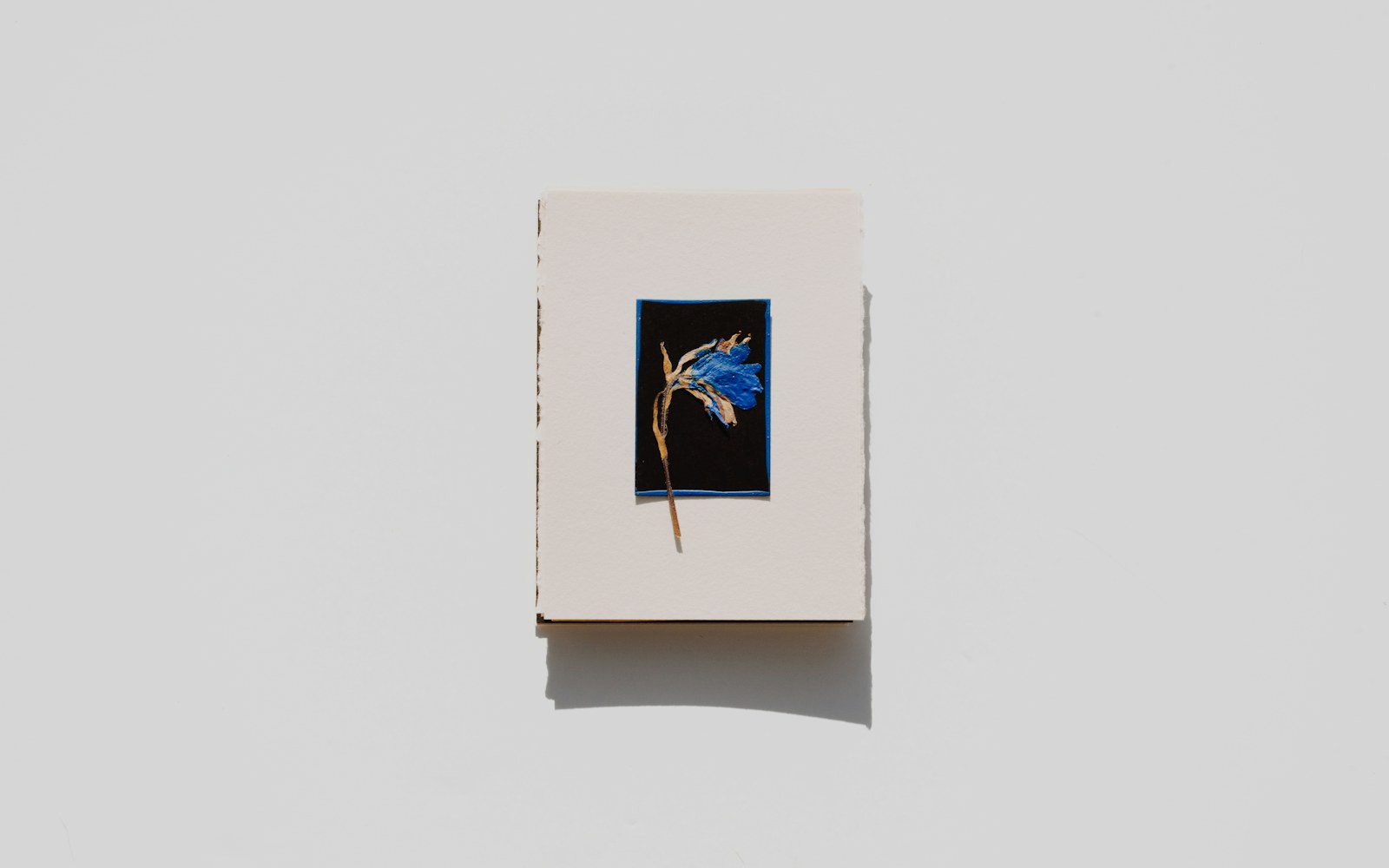 A small embroidered textile figure with a concealed wire armature standing on a worktable beside fabric, thread and felt.