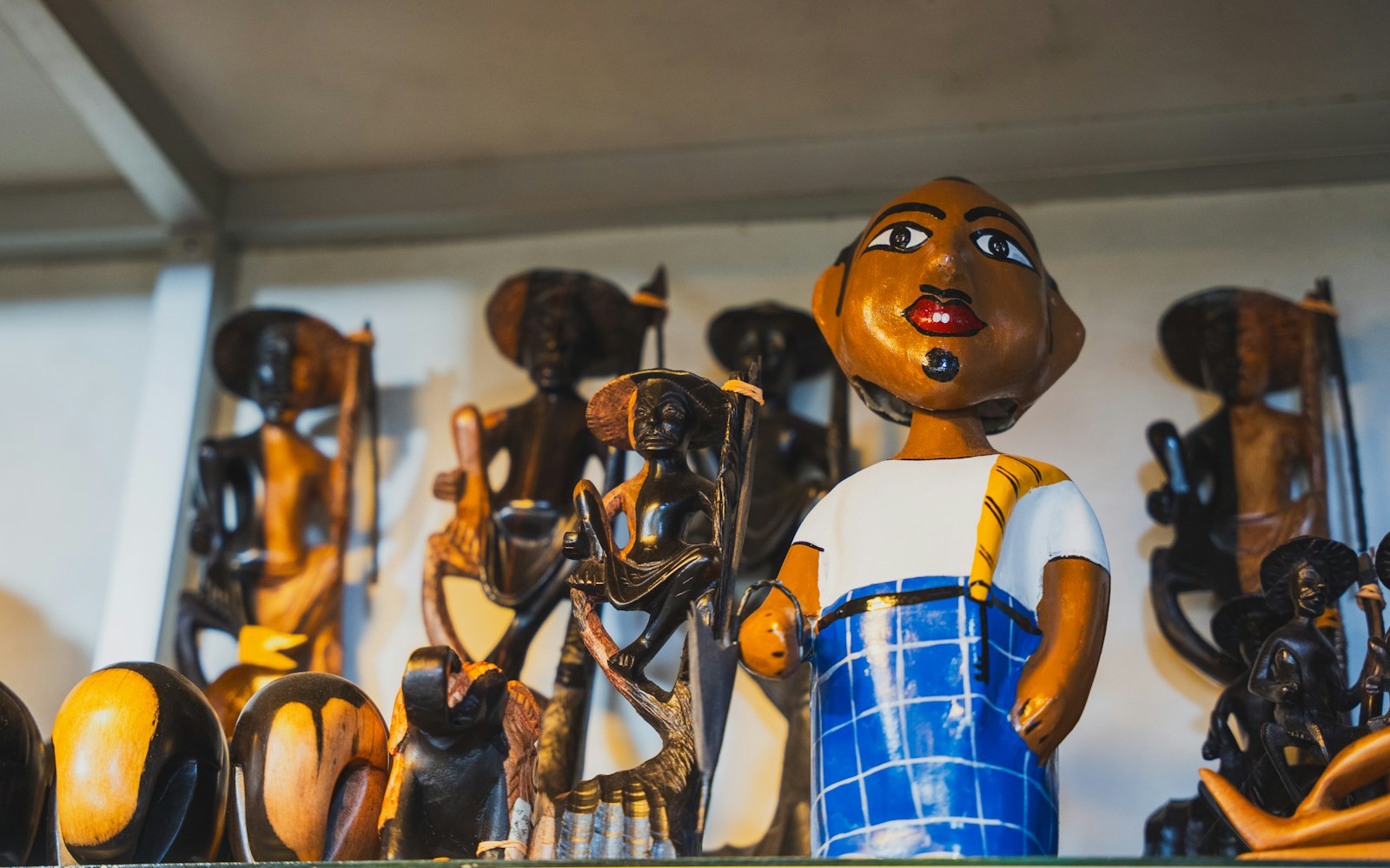 A mixed-material art doll on a clean shelf beside a soft brush and archival storage box