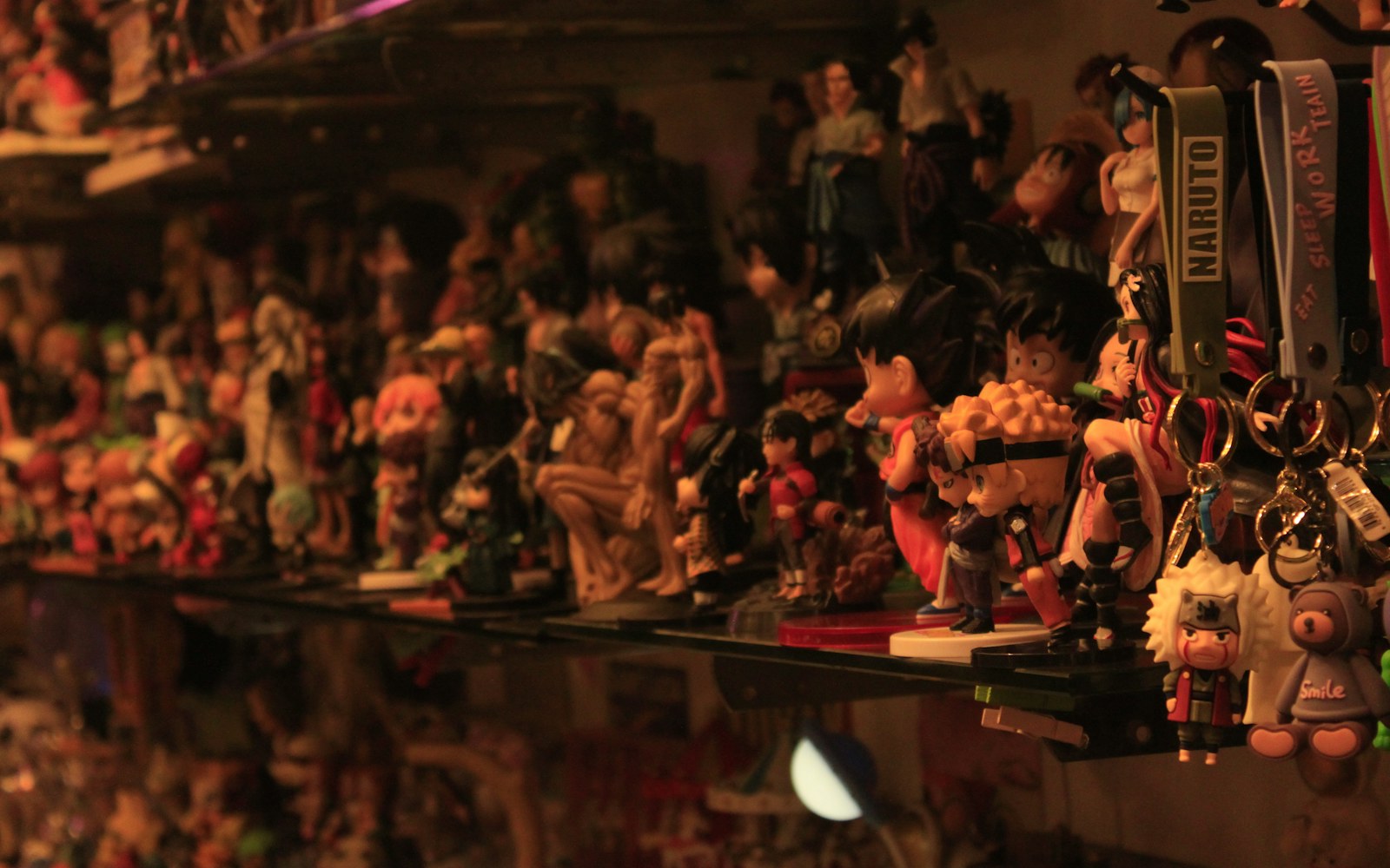 A felted textile art doll displayed on a clean shelf beside a glass case and archival storage box