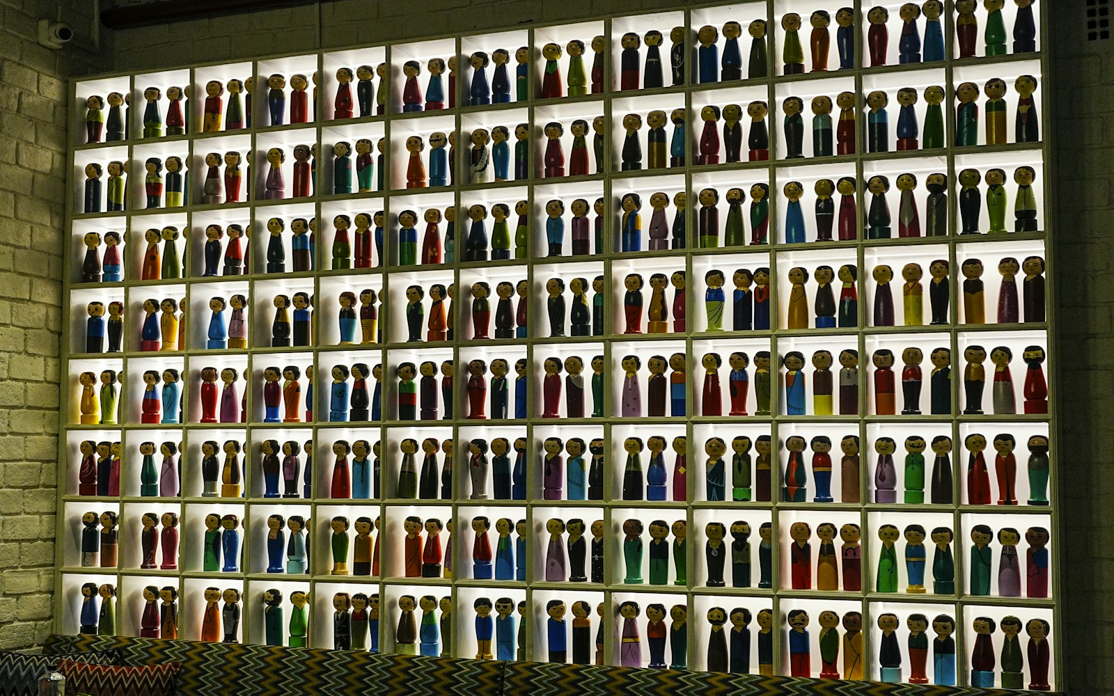 A carefully arranged shelf of handmade dolls on individual supports in soft indirect light