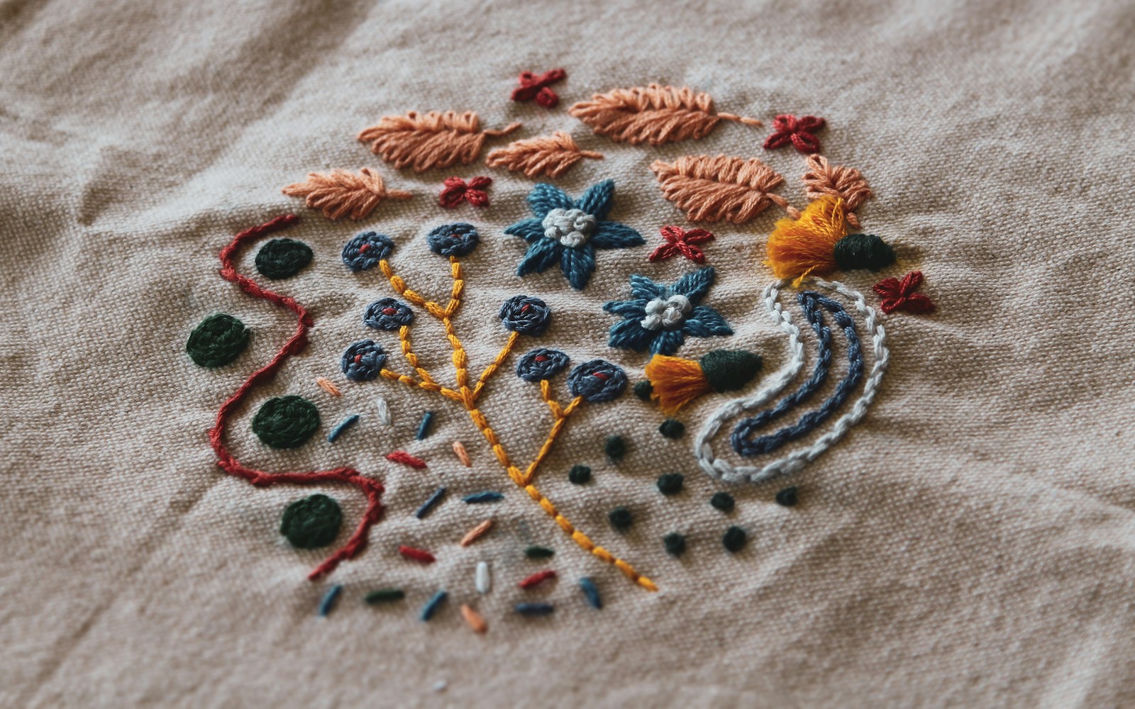 A handmade textile art doll with embroidered clothing and beadwork displayed on a smooth shelf inside a protective case.