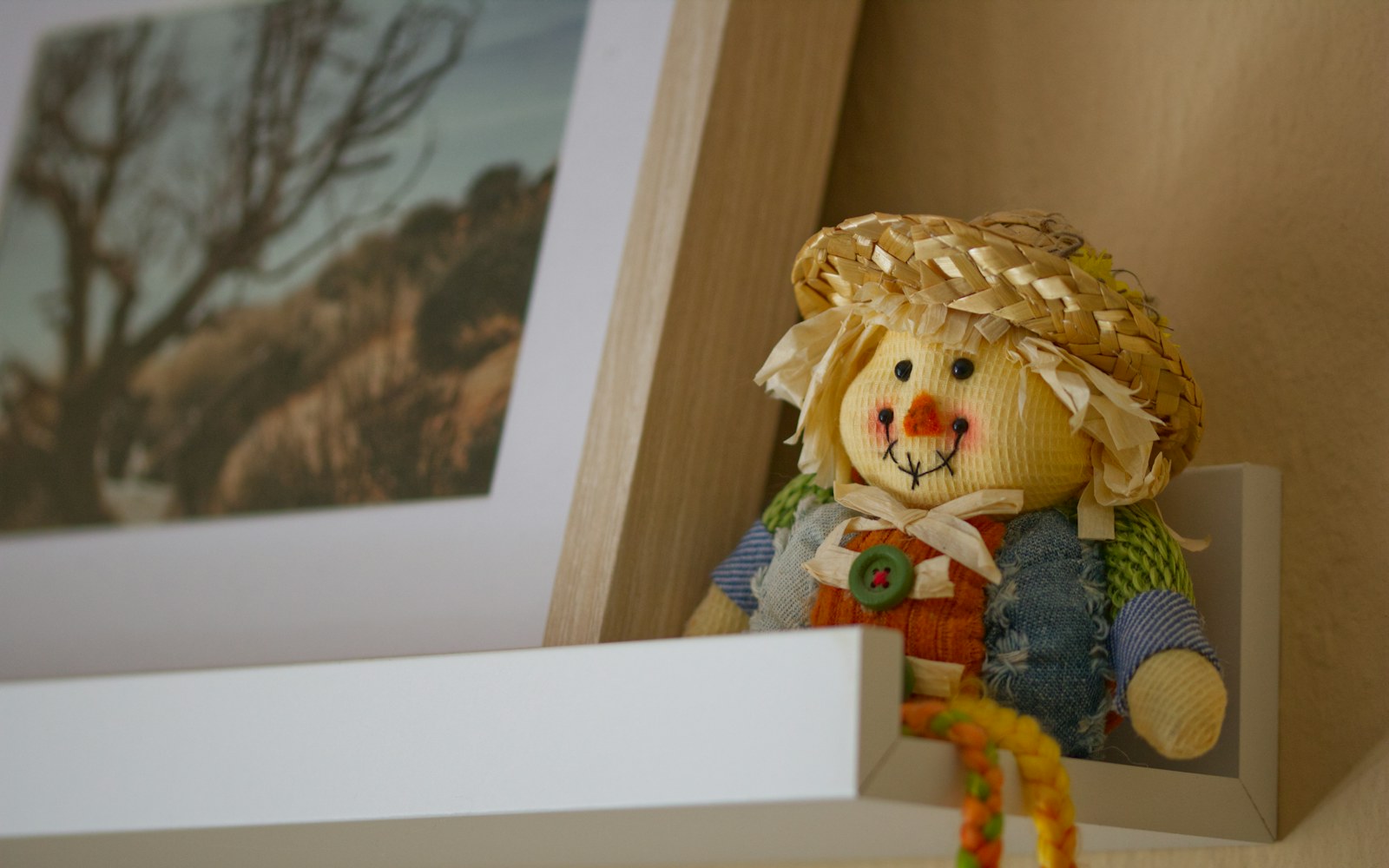 A textile art doll resting on a padded shelf in soft, indirect light