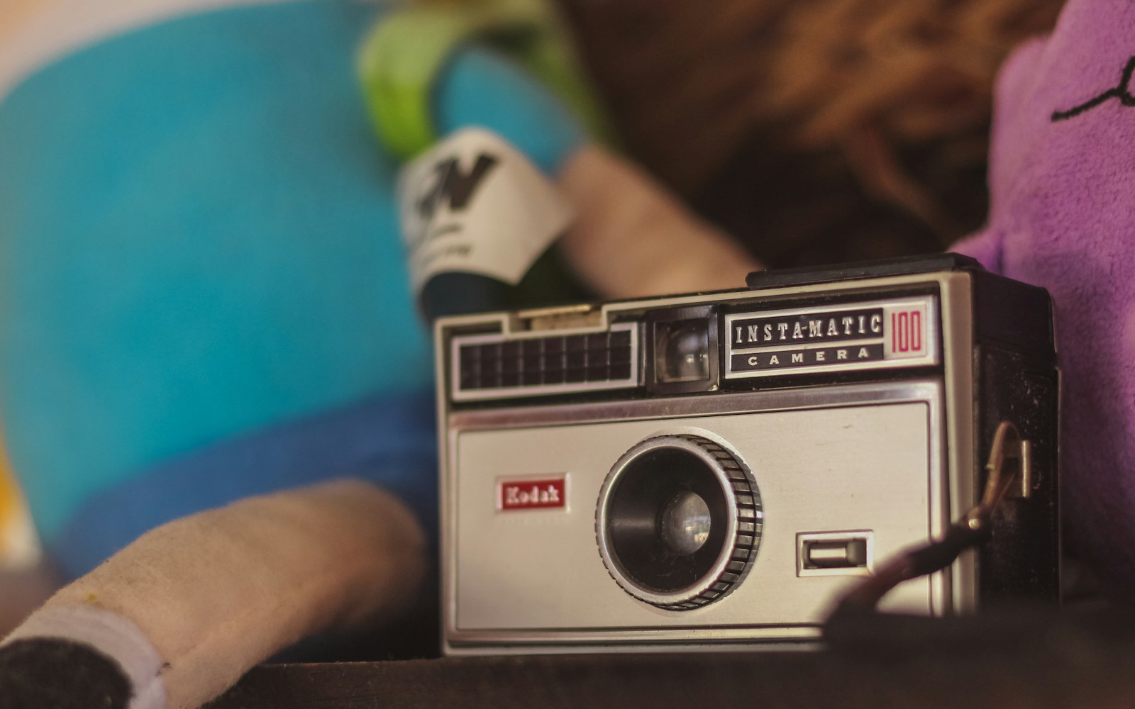 A handmade art doll beside a notebook, material samples and a camera on a worktable