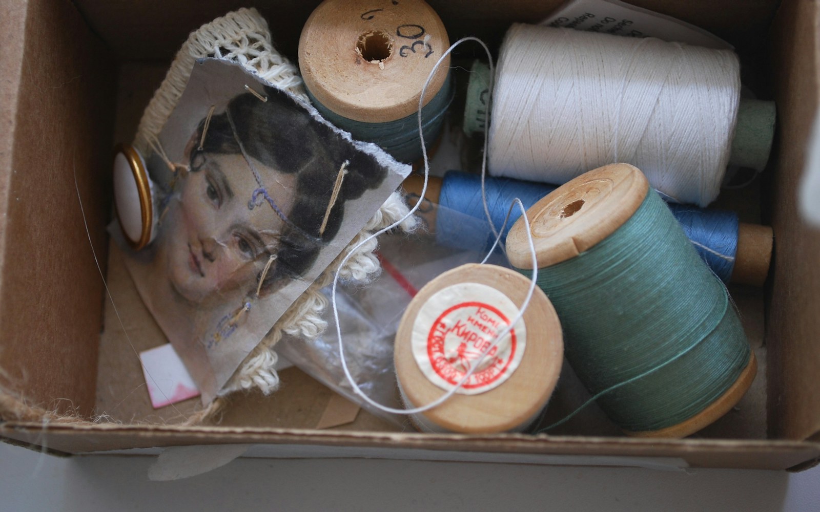 Close view of a small art doll beside paper pattern pieces, fabric scraps, pins, and a miniature garment mock-up.