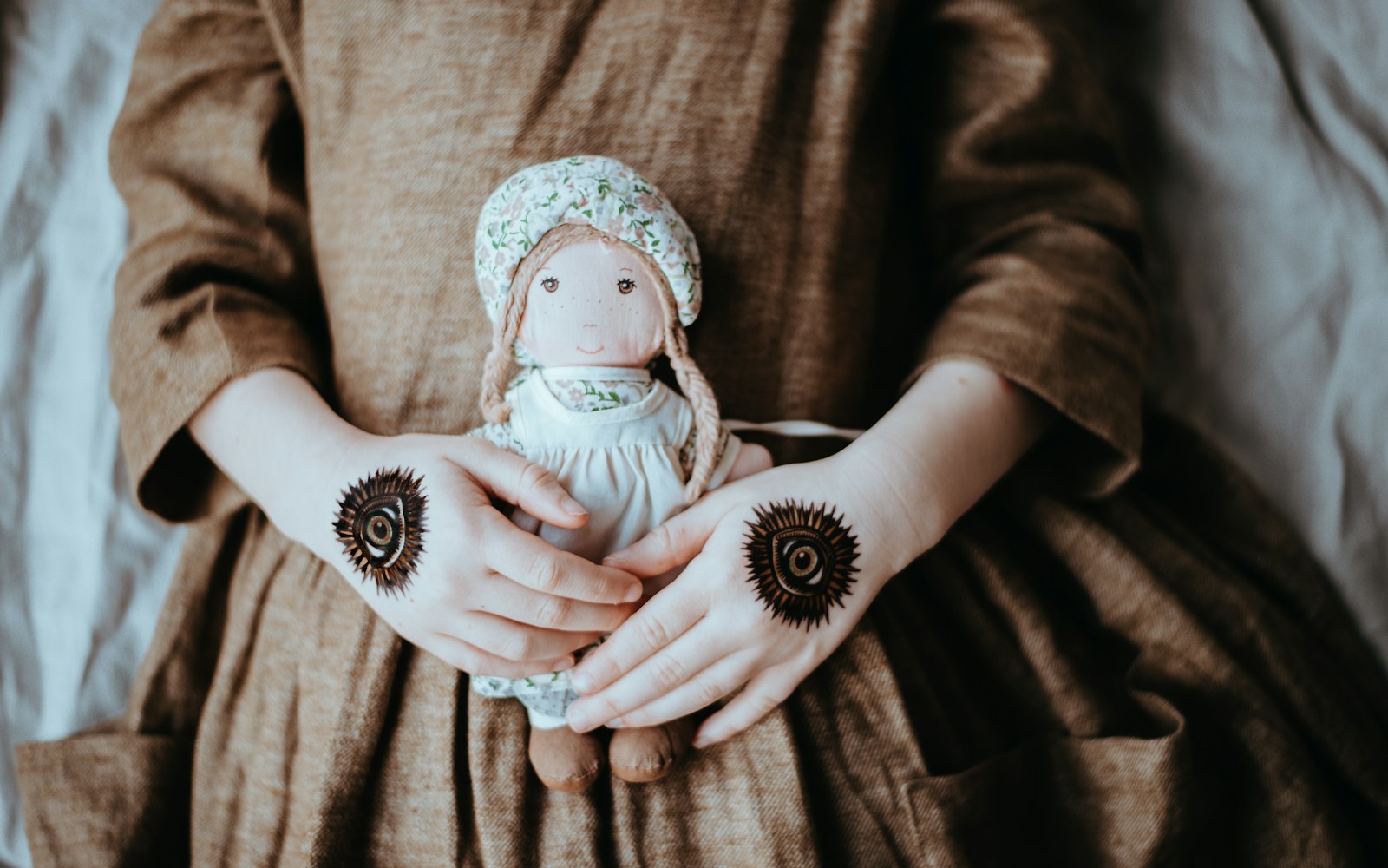A craft table with a small handmade figure, pattern pieces, thread, wire and an instruction booklet being checked against a materials list