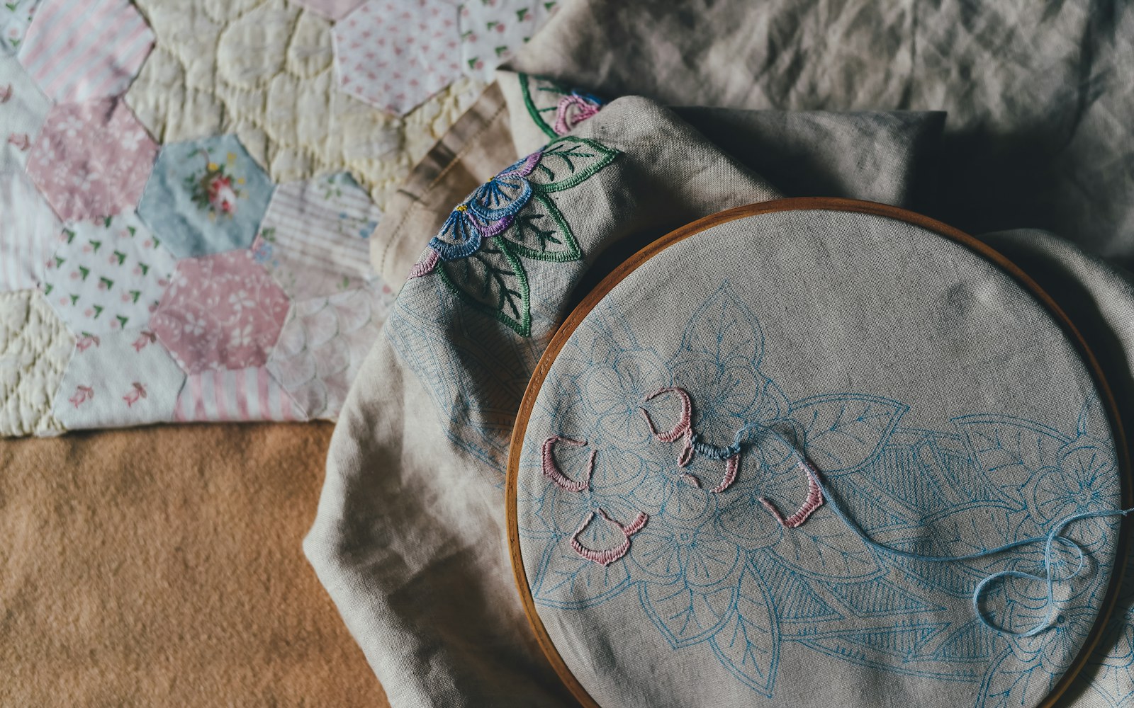 A close view of a small embroidered fabric leaf with a covered wire edge beside an art-doll costume