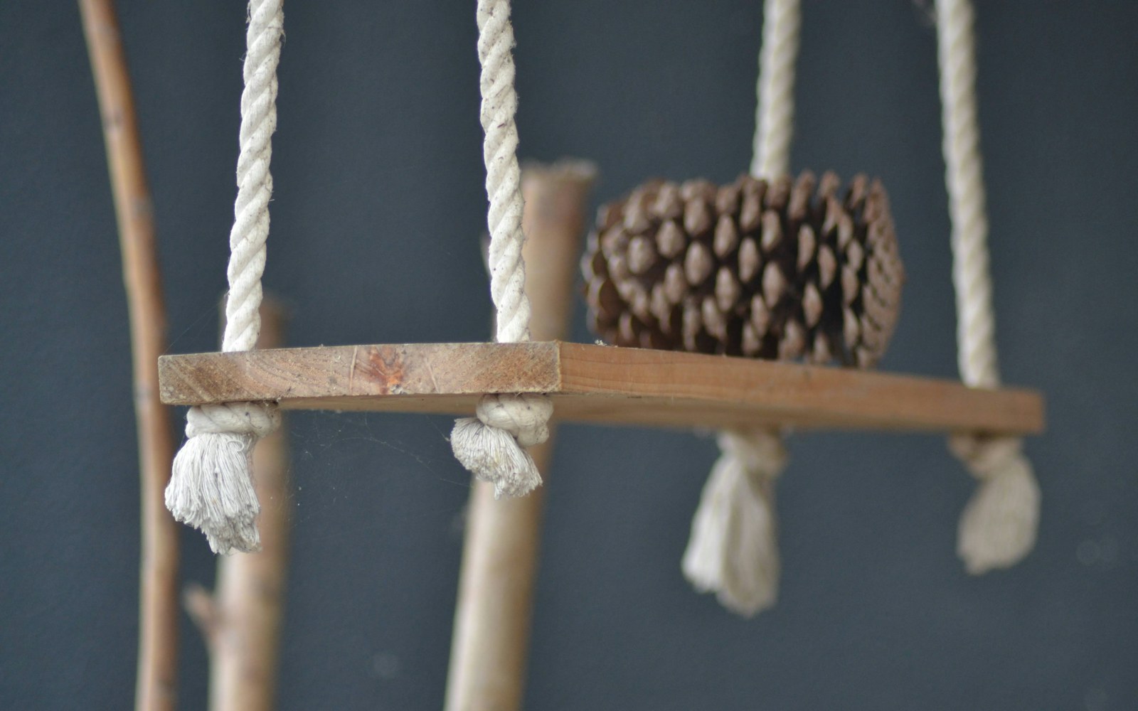 A handmade figure with bark, pinecones and twigs arranged on a clean shelf in soft natural light