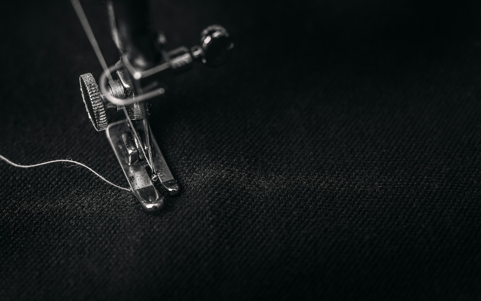 Close view of hands sewing a tiny garment in lightweight fabric beside paper pattern pieces and a small articulated art doll.