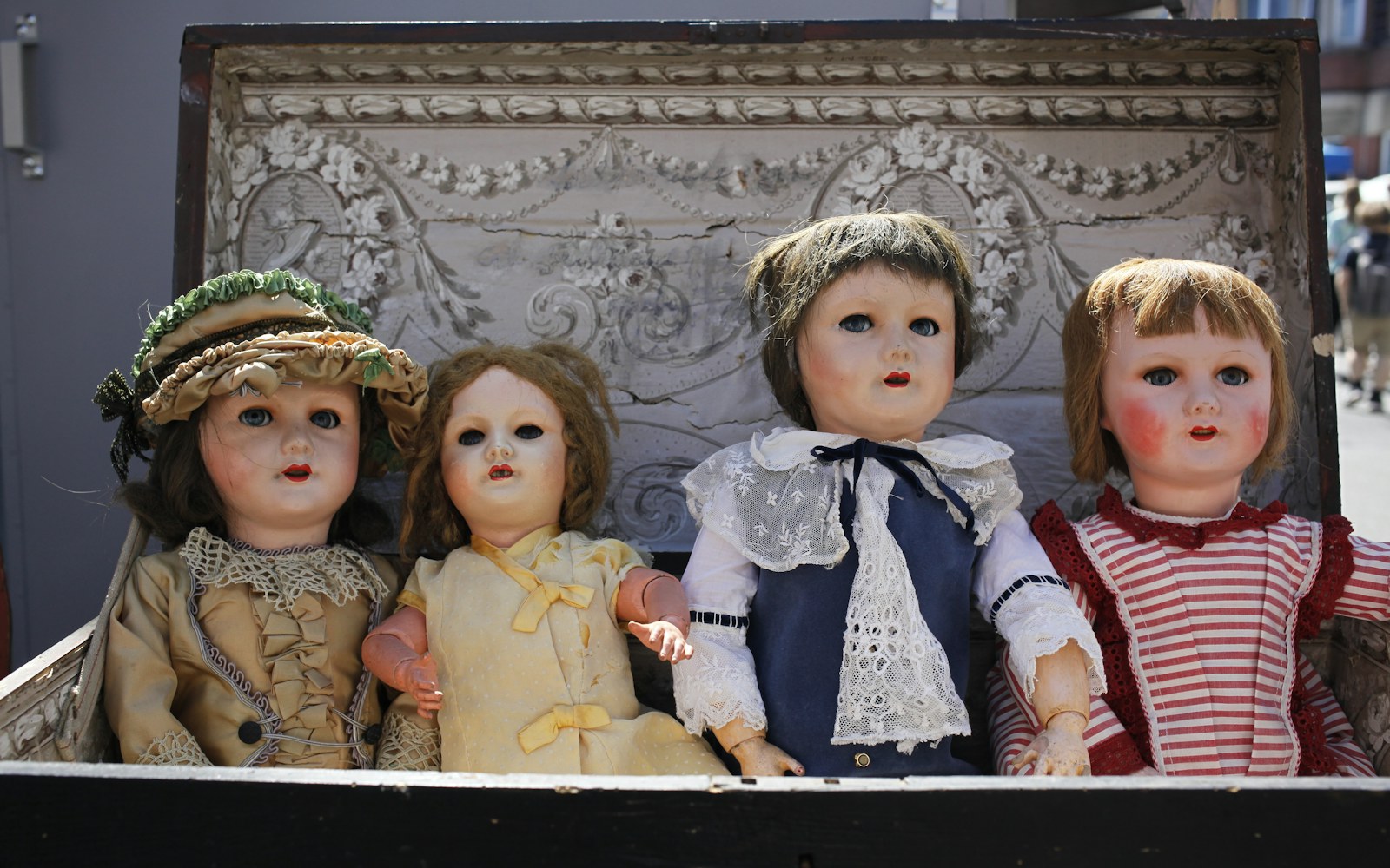 A handmade textile doll in layered clothing being carefully supported with white tissue inside a lined storage box.