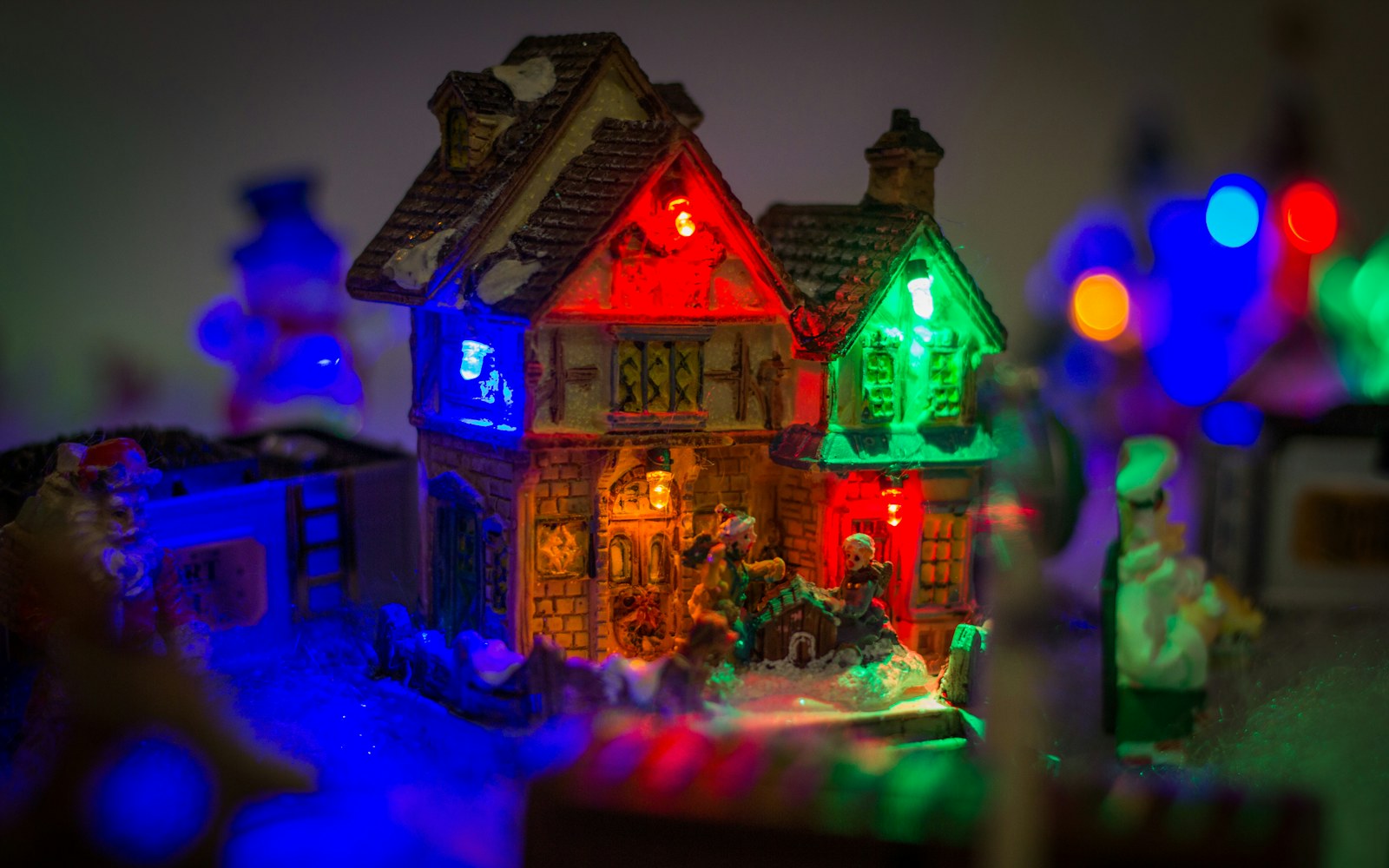 Close view of a handmade miniature figure in a display setting with a small LED light, visible cable route, and accessible battery pack nearby.
