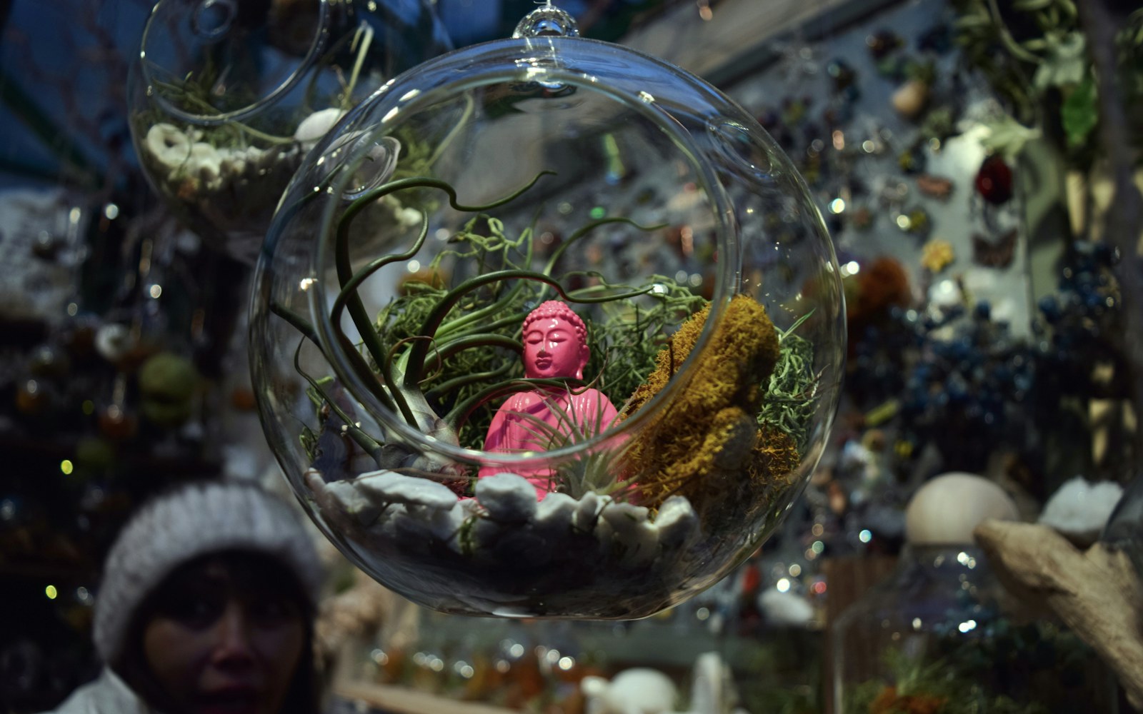 Tiny wire-and-fabric botanical accessories arranged beside an art doll on a protected display base