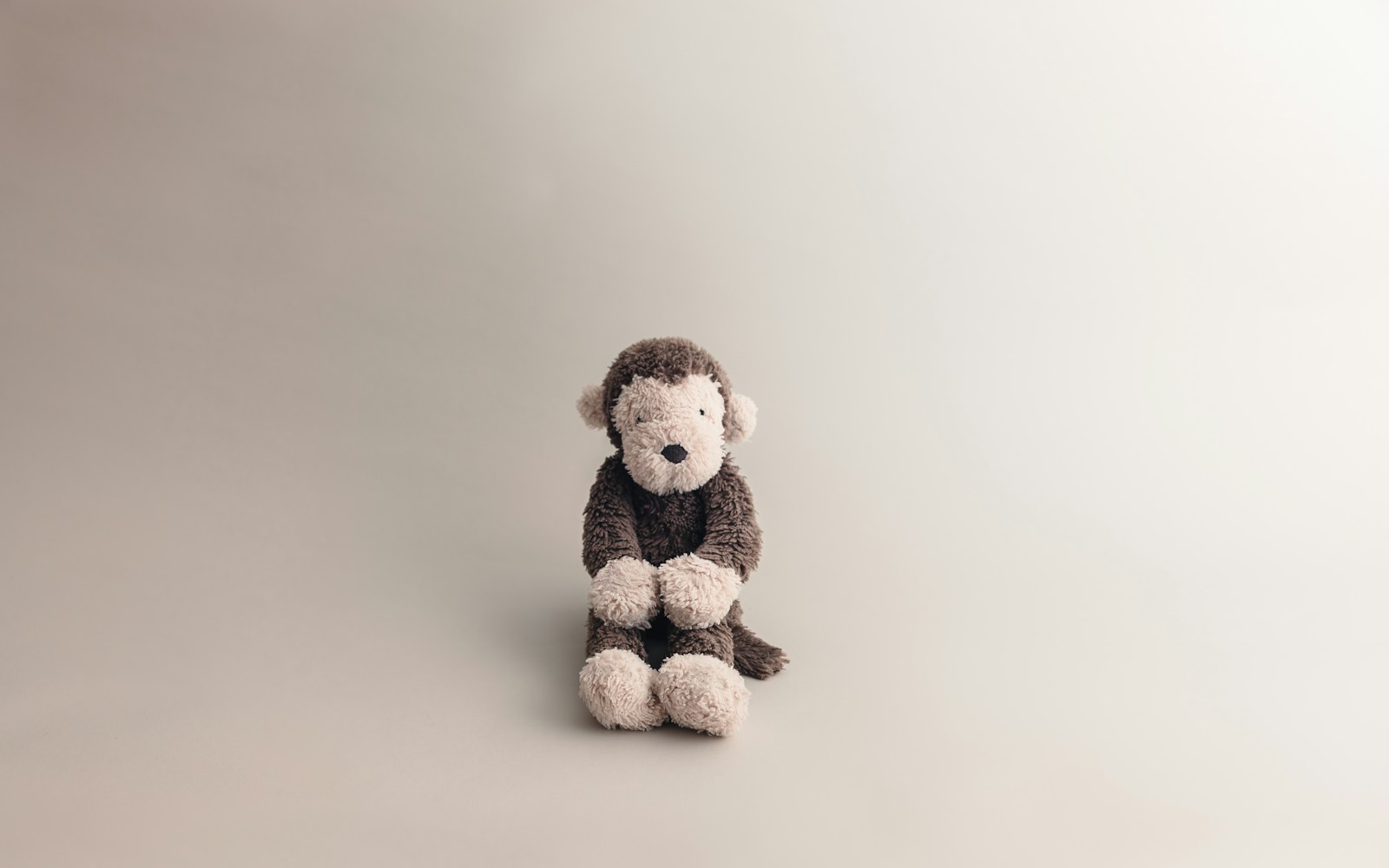 Close view of a handmade wool doll head being shaped with a felting needle on a foam work surface.