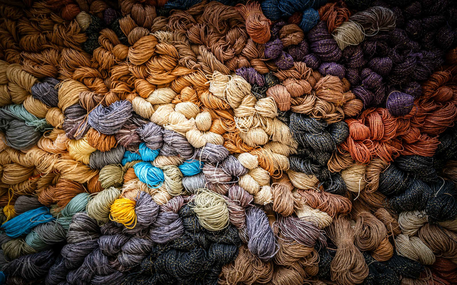 Close-up of assorted naturally coloured wool roving and wool locks arranged beside small white fabric test swatches on a clean worktable.