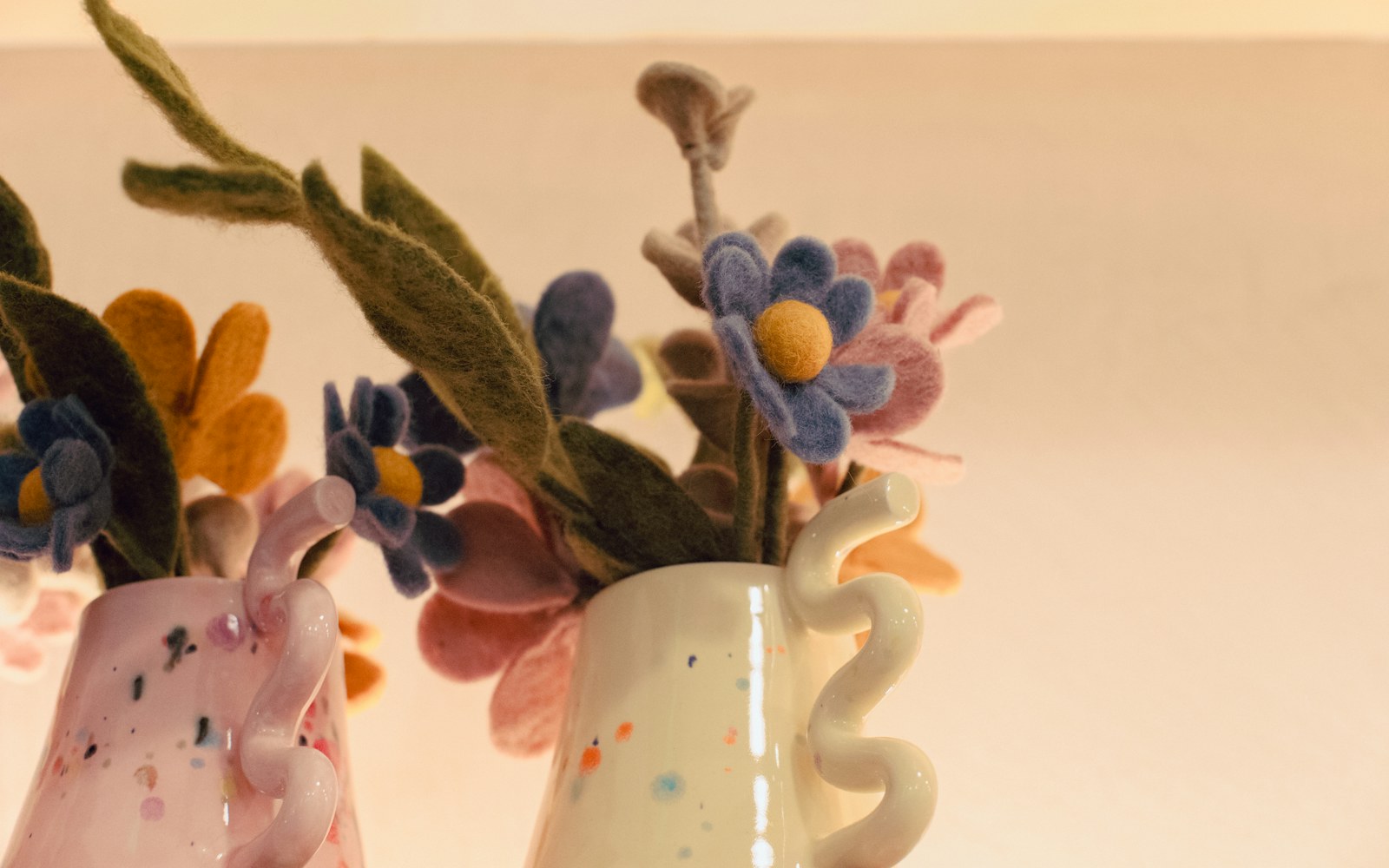 Needle-felted dolls made from plant-dyed wool in soft earthy colours on a plain studio background