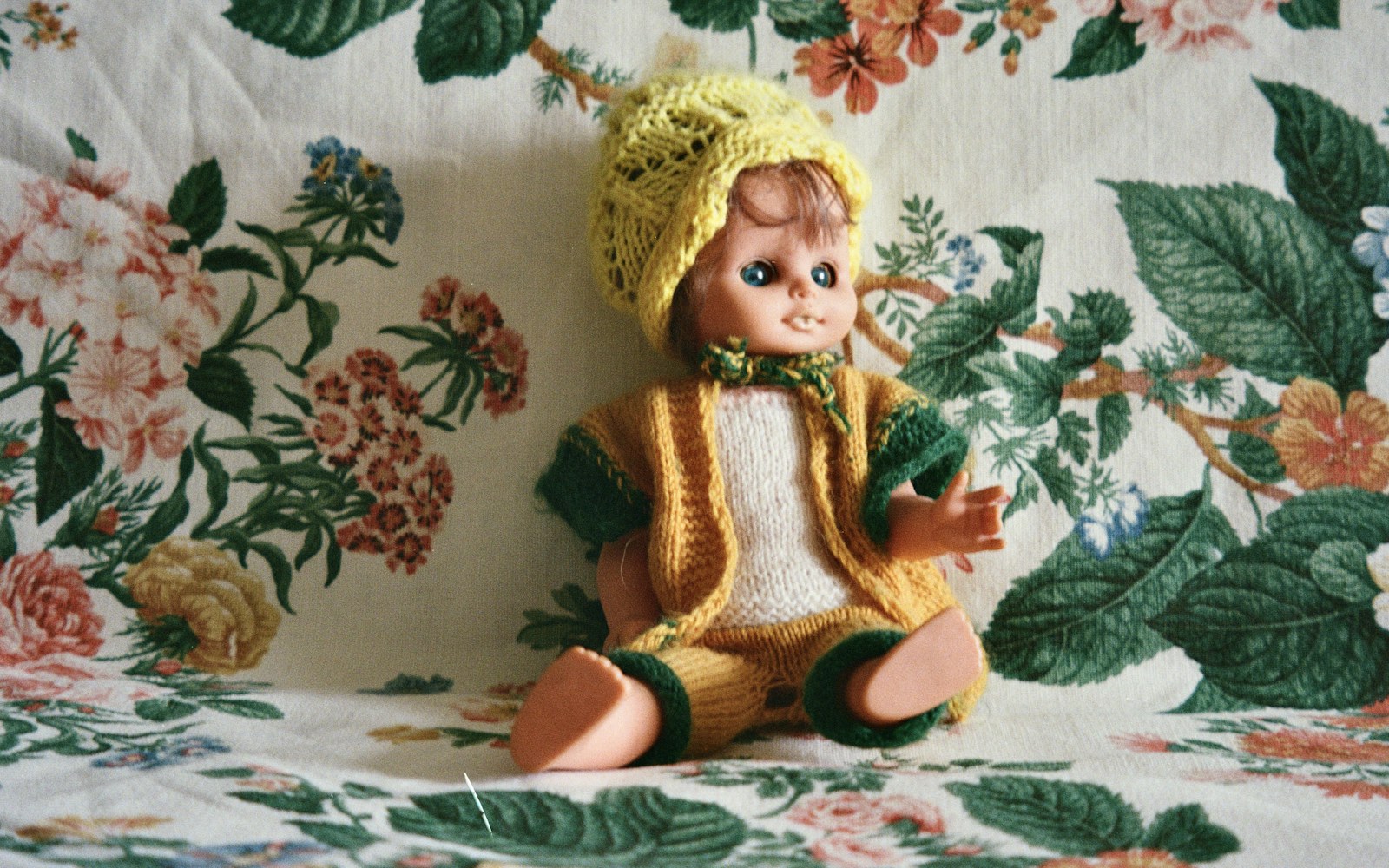 A miniature lined jacket for an art doll on a sewing table, with tiny fabric pieces, scissors, and a pressing tool nearby.