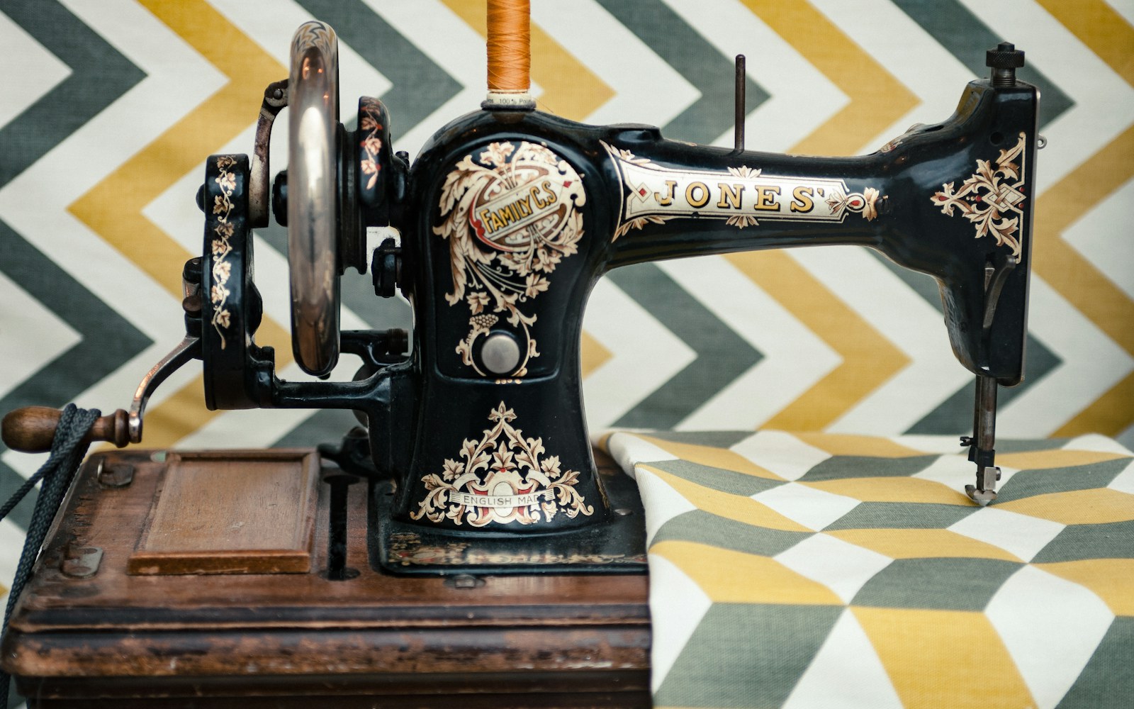 Close view of embroidered fabric doll panels, lining fabric, thread, scissors, and a hand-sewing needle arranged on a worktable.