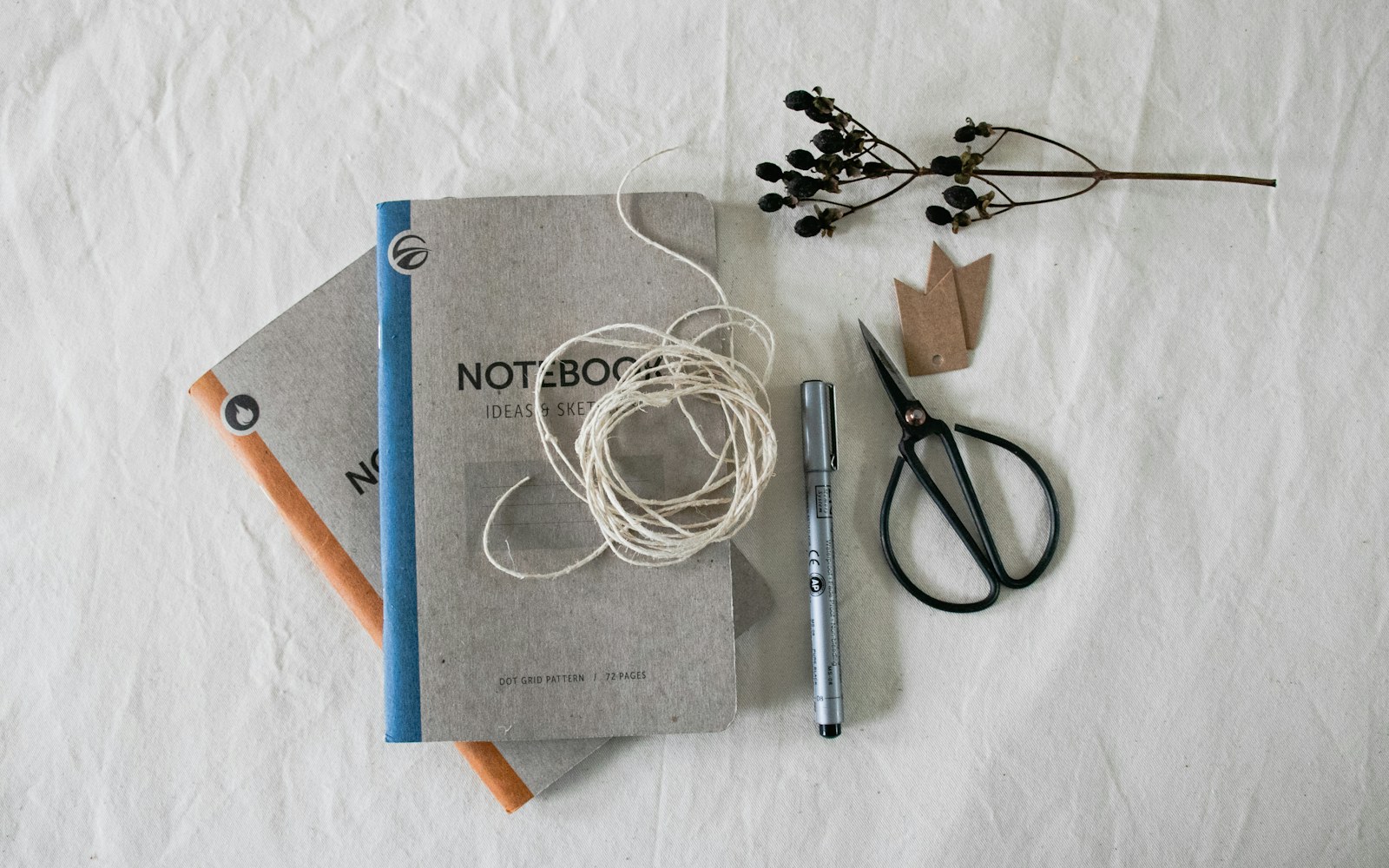 A handmade art doll beside a notebook, measuring tape, archival labels, and detail photographs