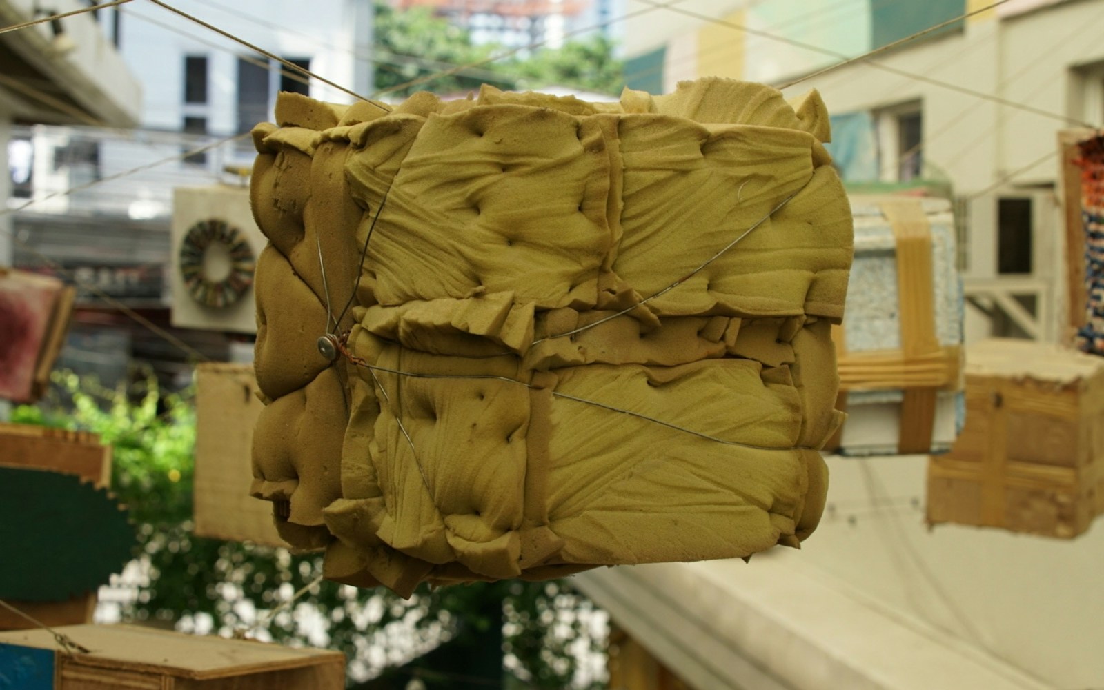 Close view of a handmade wire armature shaped into a small doll body beside padding and sewing materials on a worktable.