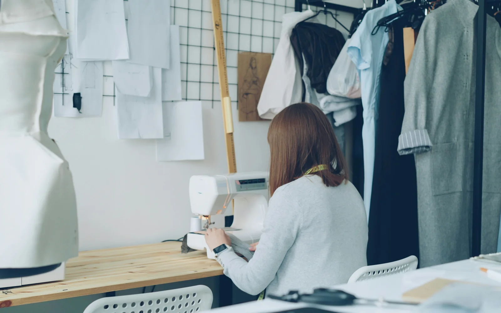 A seamstress working at a sewing machine in a bright studio.